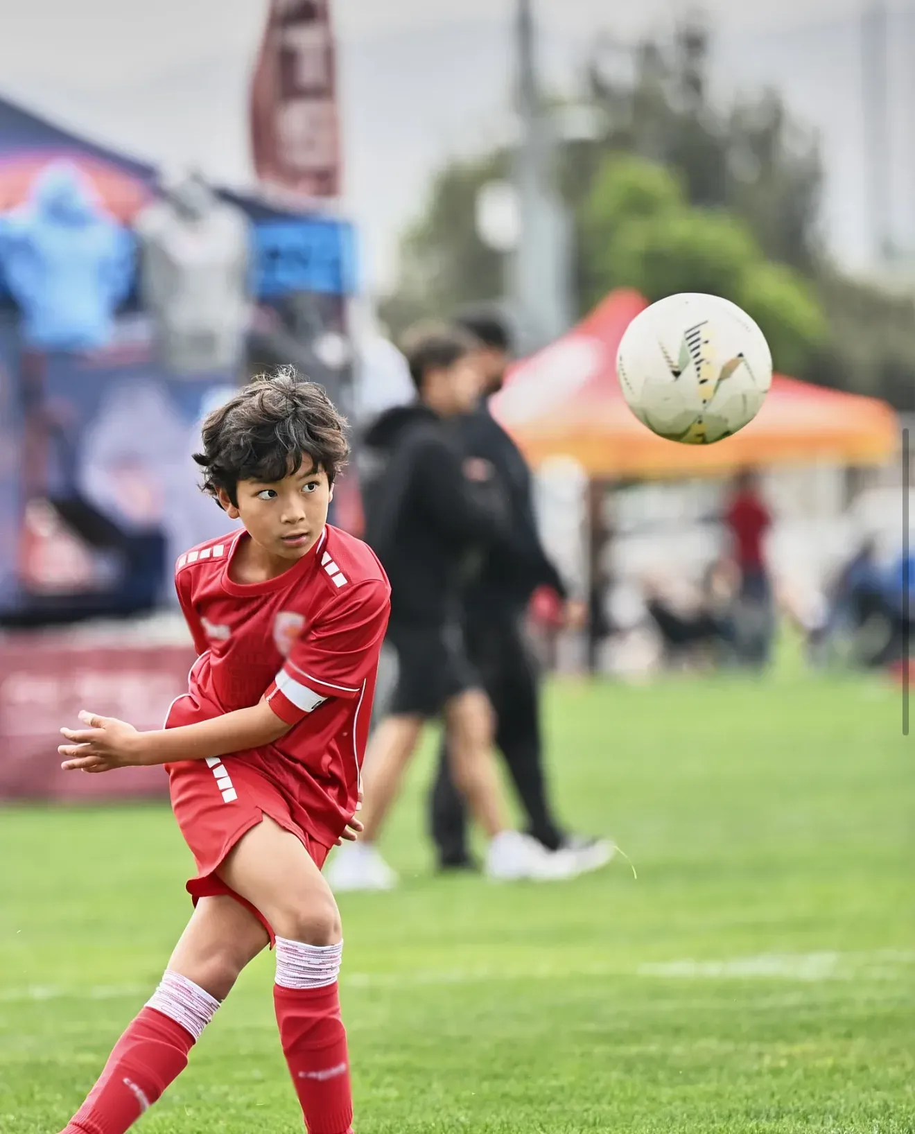 A young player mid-kick at a beach soccer game